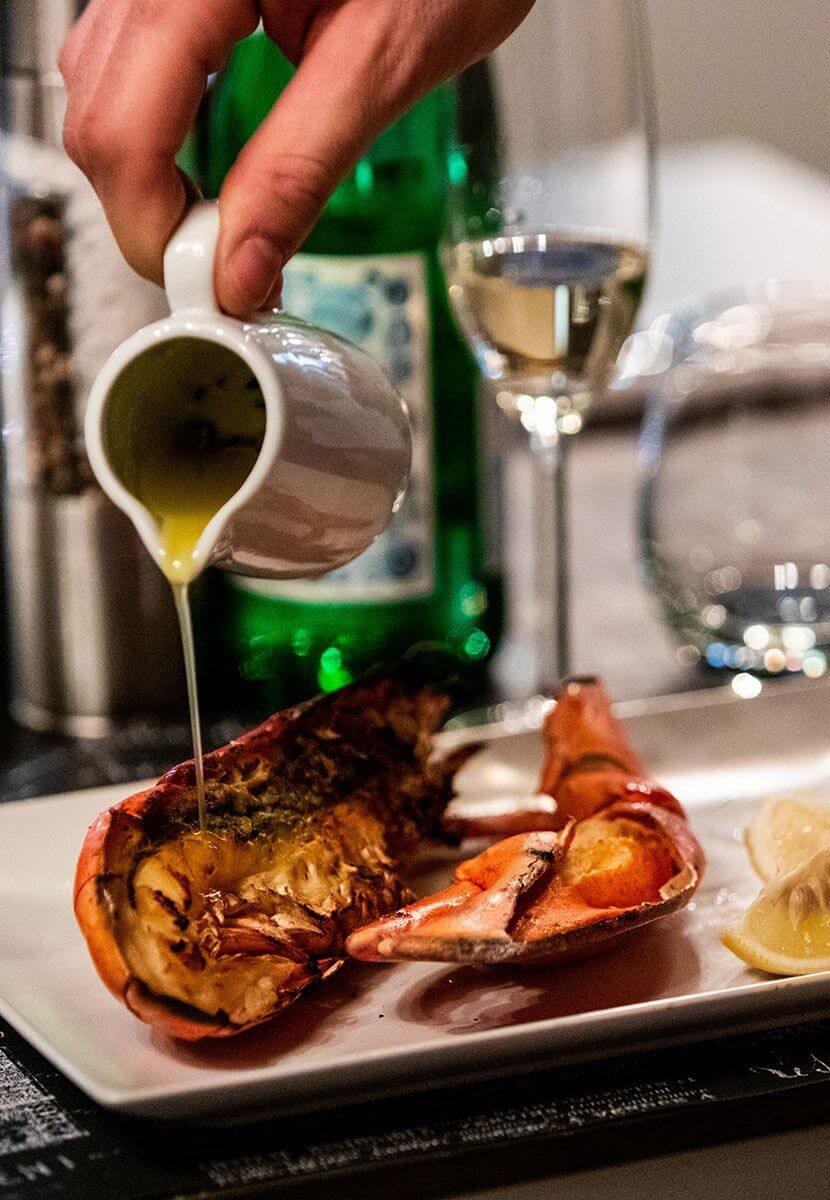 Hand pouring butter on a lobster